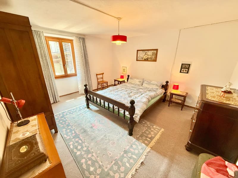 bedroom with a bed, rug, lamps, wooden cabinets, window, picture frames, side table, wooden chair