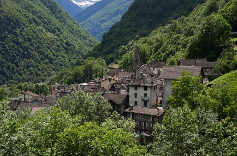 Old village houses, made of stone, situated in the mountains with narrow streets, surrounded by thick green vegetation