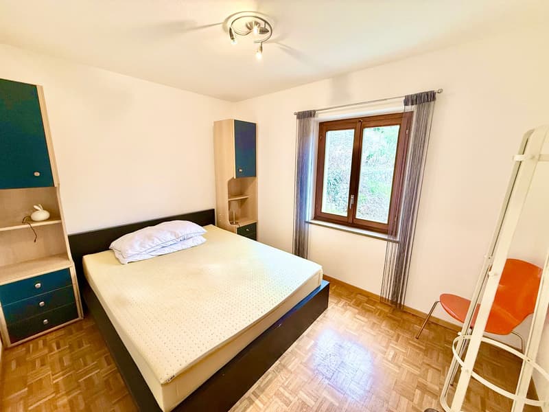 Single bed with white mattress, 2 pillows, 2 dressers, shelf, orange chair, ladder, double window with curtains, wooden floor, ceiling lamp