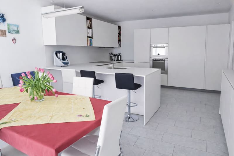 white modern kitchen with counter top seating, two stoves, dishwasher, coffee machine, cupboards, tiles