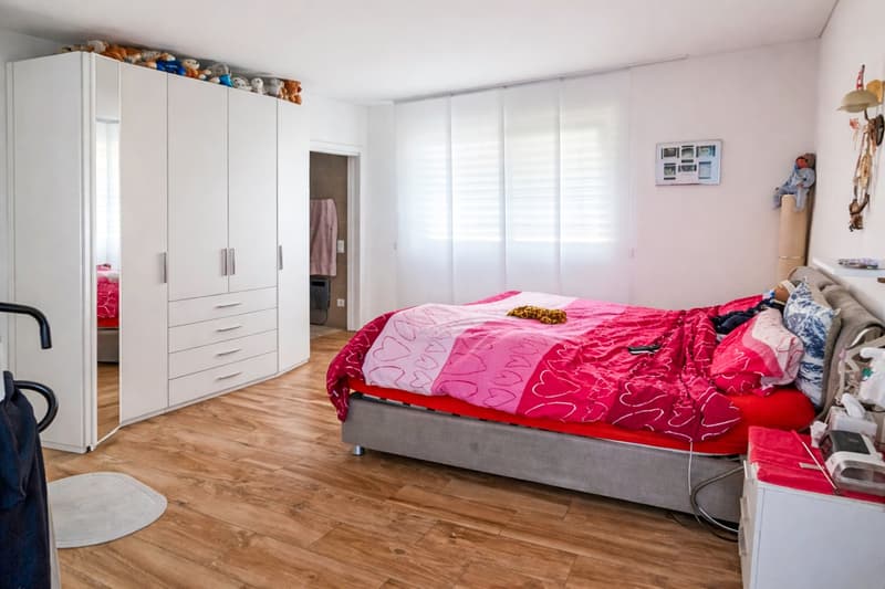 a room with a bed, large closet, wooden floor