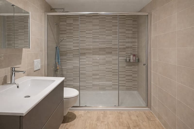 modern design, white sink, white toilet, glass shower enclosure, shower head, tiled floor, power outlet