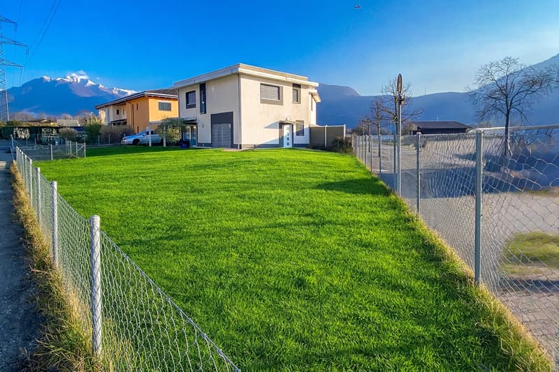 Detached house, modern architecture, fenced lawn, mountains in background