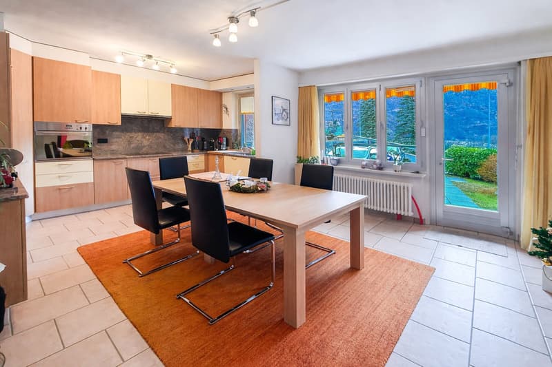 light oak kitchen cabinets, central island, stainless steel oven, dining table, wooden floor, large windows with mountain view