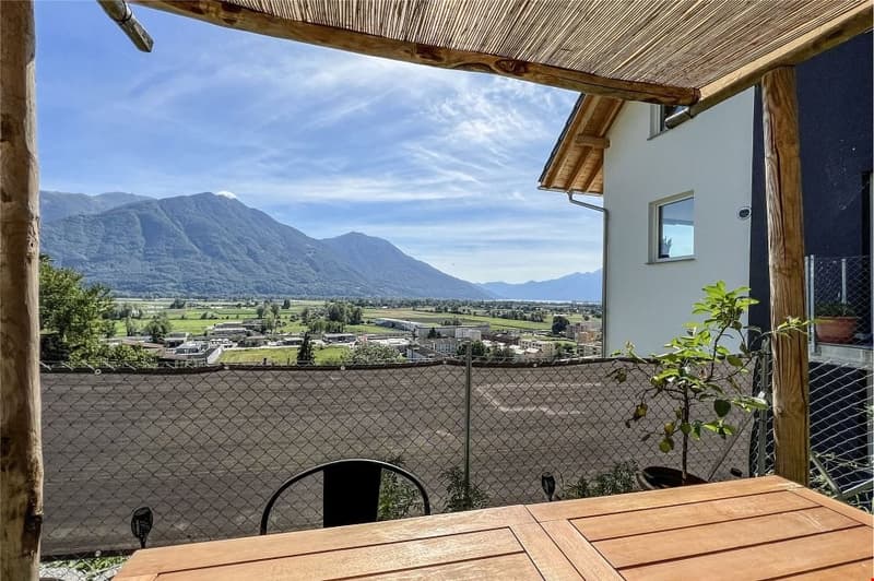 View of mountains, wooden table, chairs, wooden pergola, potted plants