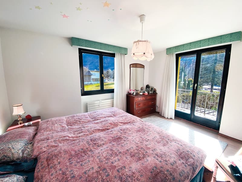 large bed, pink bedspread, two bedside tables, lamp, mirror, wooden chest, double doors to balcony, curtains, star stickers on ceiling