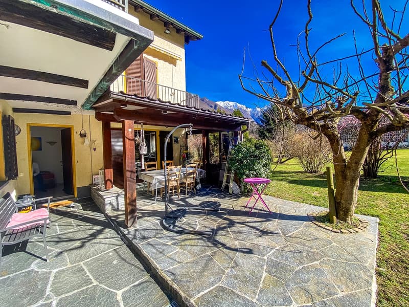 House with a terrace, dining table, chairs, bench, tree, and a view of the mountains