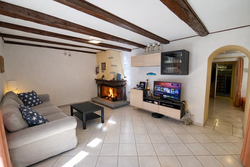 white tile floor, fireplace, TV with media stand, sofa, wooden ceiling beams