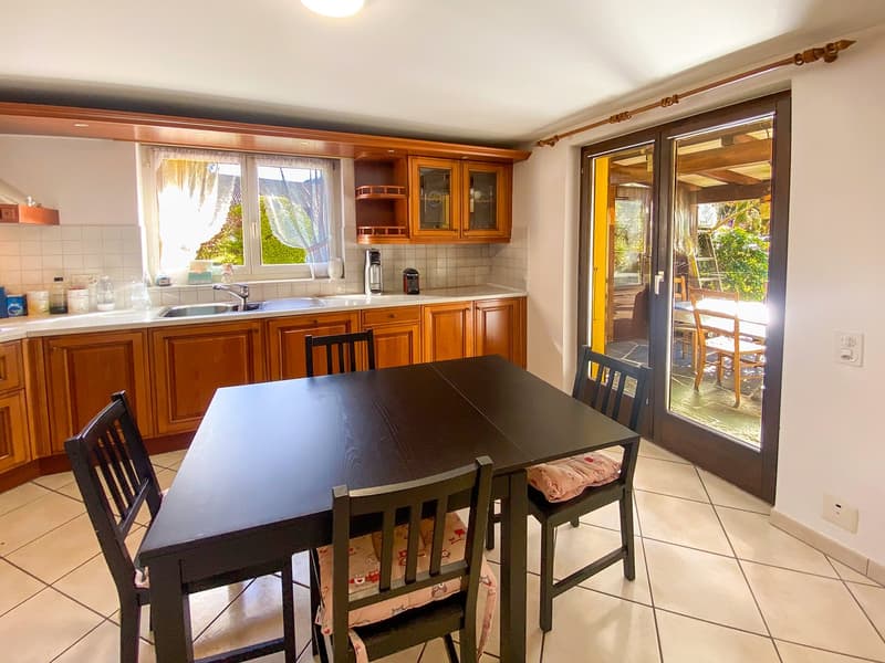 open plan kitchen with dining area, wooden cabinets, tiled floor, glass sliding doors to patio, bright natural light
