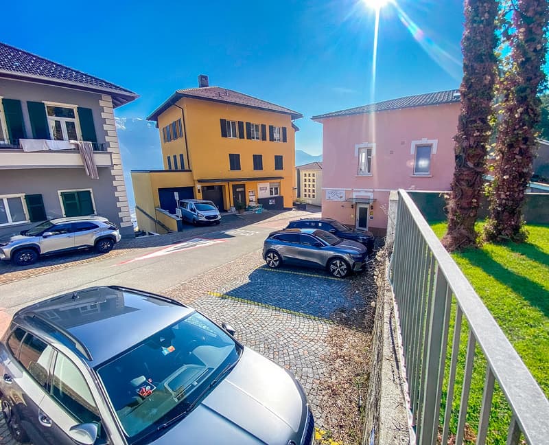 Three buildings with three cars parked in front of each, cobblestone street