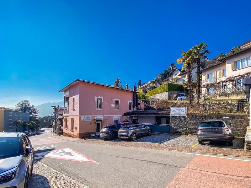 Exterior of a pink building with several cars parked in front and a side entrance