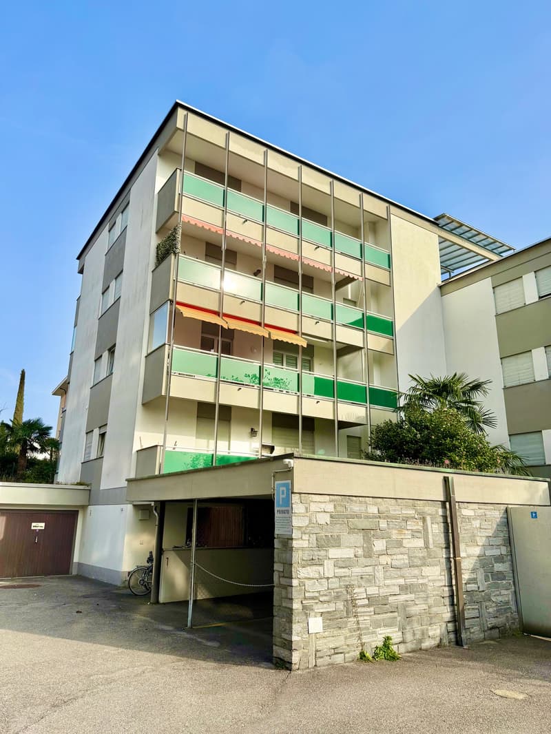Multi-story building with balconies, parking area, and a bicycle