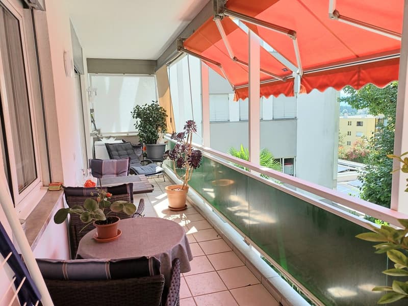 Balcony with awning, chairs, table, plants, glass railings
