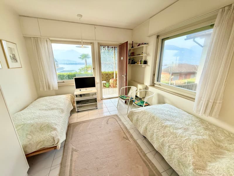 Two single beds, rug, TV, chairs, shelves, picture frames, windows with curtains