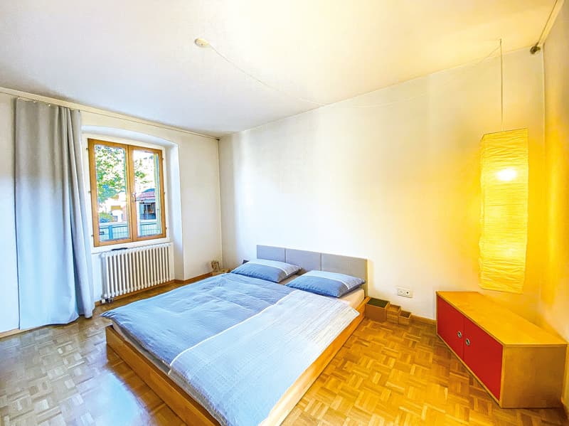 bedroom with bed, window, radiator, wooden floor, cabinet