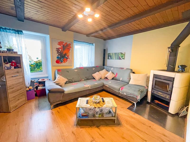 L-shaped sofa, coffee table, fireplace, wooden floor, wooden ceiling, windows with curtains