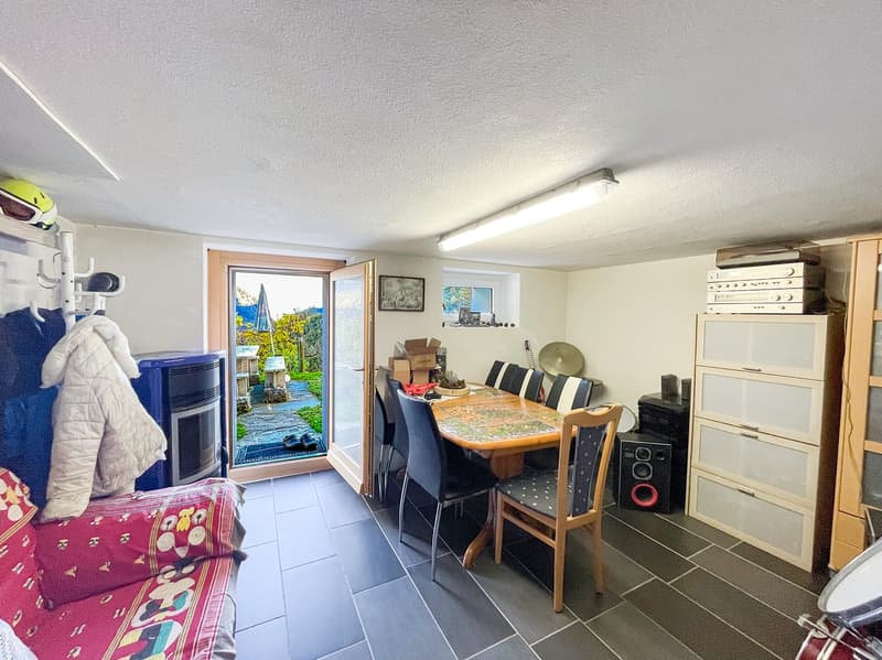 Dining room with table and chairs, open door to balcony, storage boxes, speakers, coat rack, sofa with pillows
