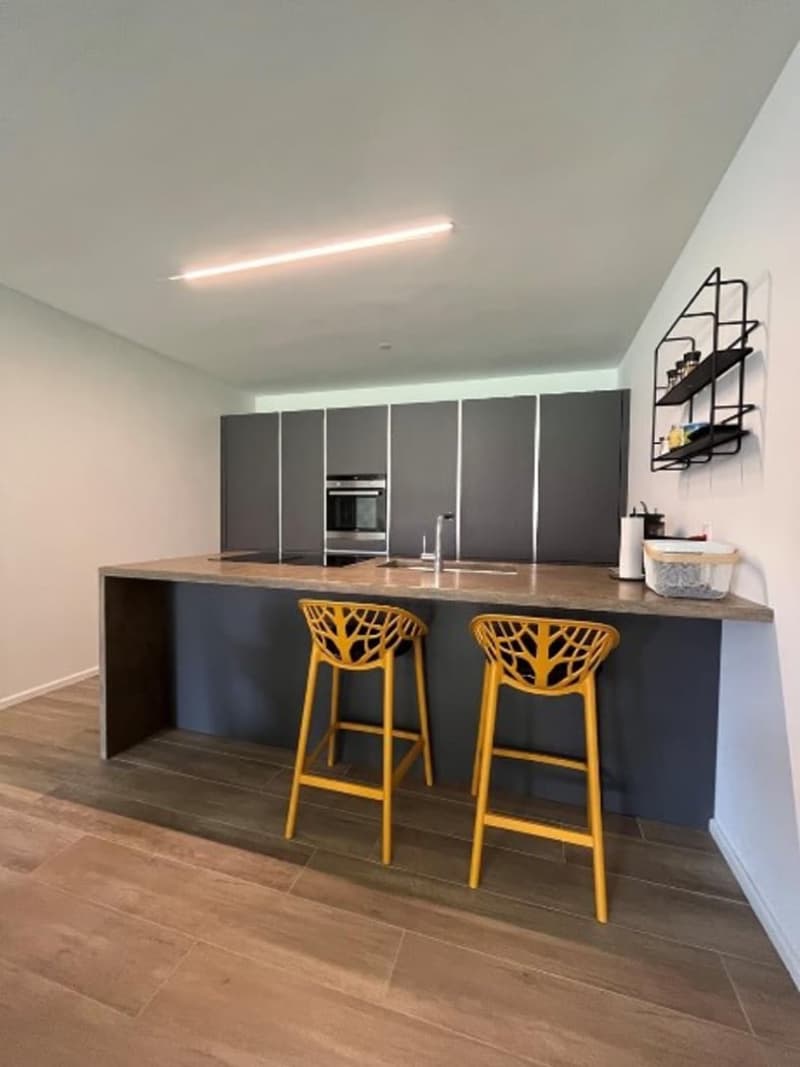 modern kitchen with island, gray cabinets, yellow chairs, wooden floor, white walls, built-in oven, sink, faucet