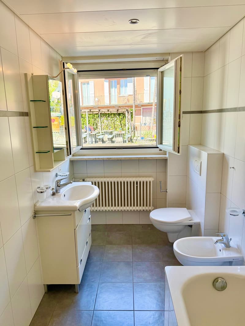 Bathroom with white tiles, white sink, white toilet, white bathtub, white radiator, open window