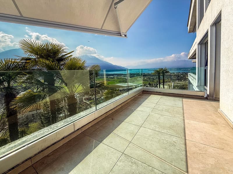 Balcony with glass railings, tiled floor, palm trees, mountain view, sea view