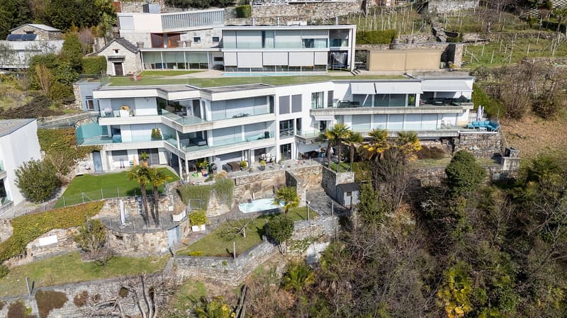Modern multi-story house, large swimming pool, multiple balconies, stone walls, green roof, garden