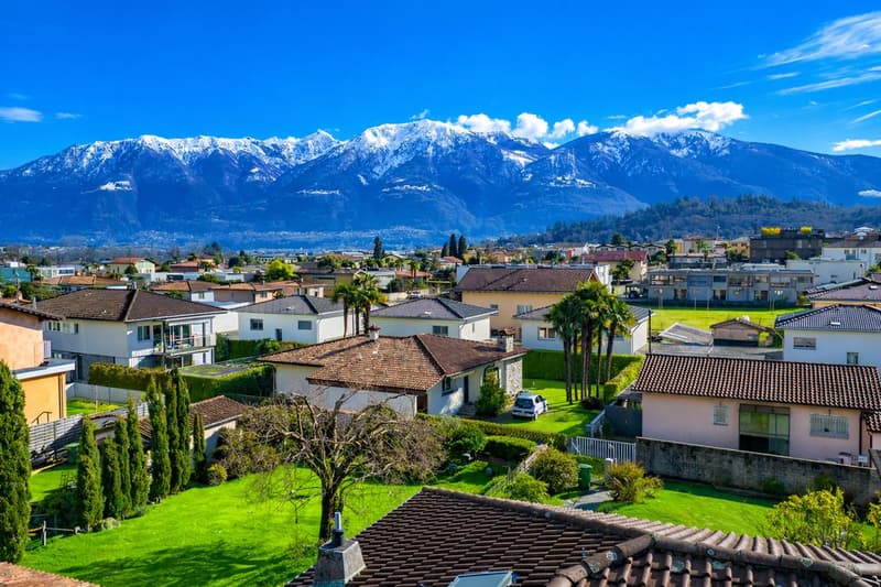 Suburban neighborhood with houses, green lawns, and a mountain range in the background
