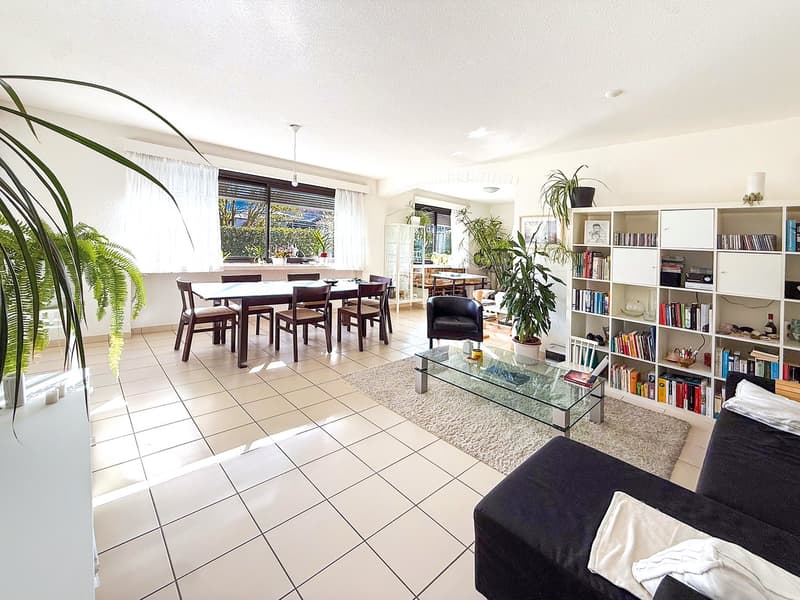 modern living room with white tiles, dining table, chairs, couch, bookshelves, plants, rug, glass table, coffee table