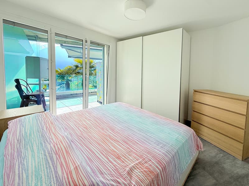 Bedroom with a bed, a wardrobe, a dresser, and a balcony with a view of the outside.