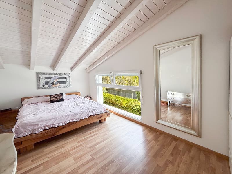 bedroom with wooden bed, wooden floor, large window, mirror, picture frame