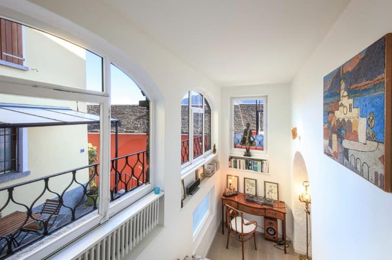 Arched windows, desk, chair, radiator, painting on wall, balcony