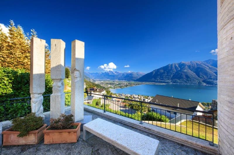 stone bench, railing, small pillars, planted boxes, mountains, lake in background