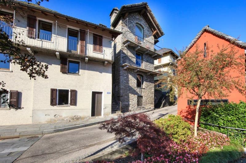 3 story buildings, balcony, trees, bushes, flowers, grey road