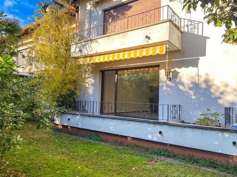 2 story house, white exterior, yellow awning, balcony, garden, metal railings