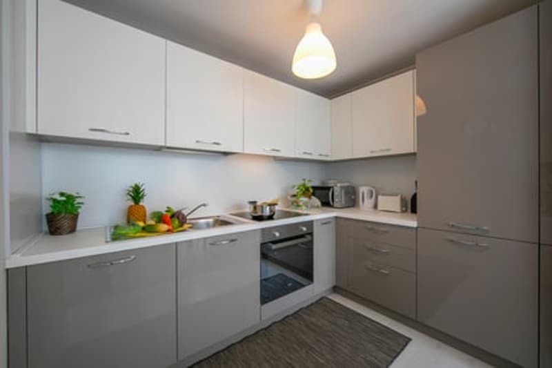 modern kitchen with white cabinets and grey countertops, integrated appliances, open shelving