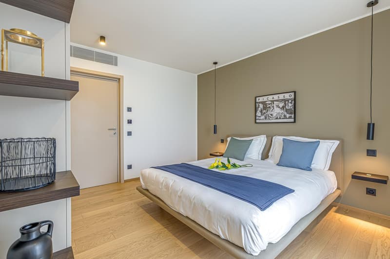 bed, nightstand, shelves, air conditioning vents, picture frame, warm lighting