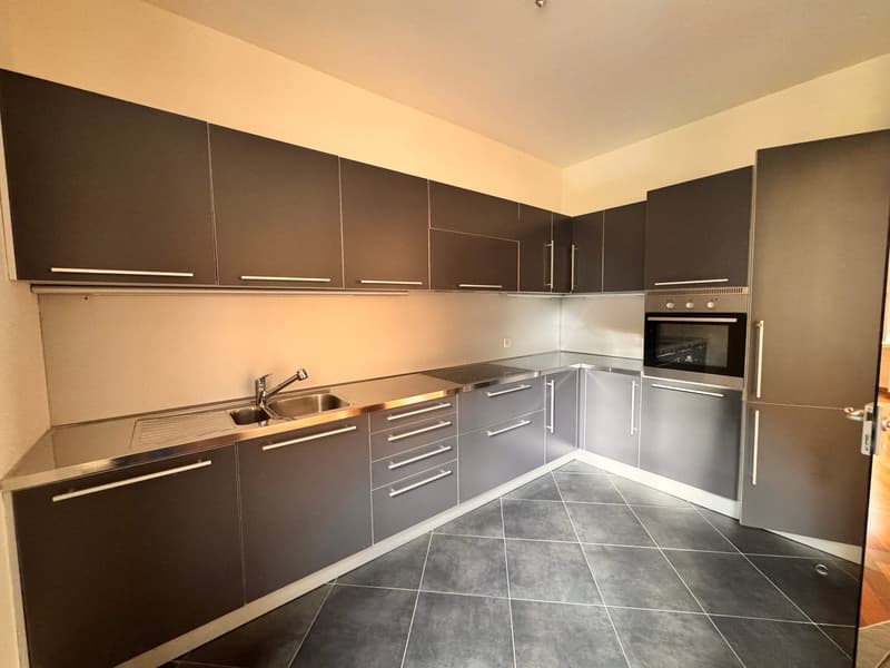 modern kitchen with stainless steel countertops, built-in oven, dishwasher, and washing machine