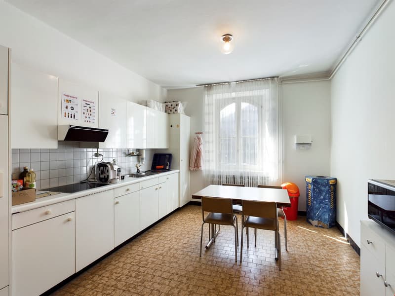 Spacious kitchen with white cabinets, tiled backsplash, and a dining table. The kitchen is equipped with a dishwasher and other appliances.