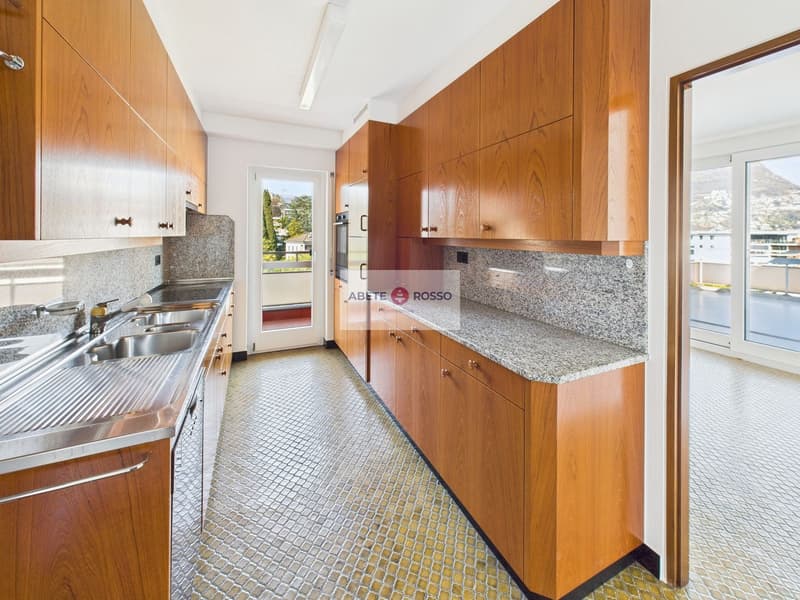 Spacious kitchen with wooden cabinets, granite countertops, stainless steel sink, and dishwasher. The kitchen has a tiled floor and a window providing natural light.