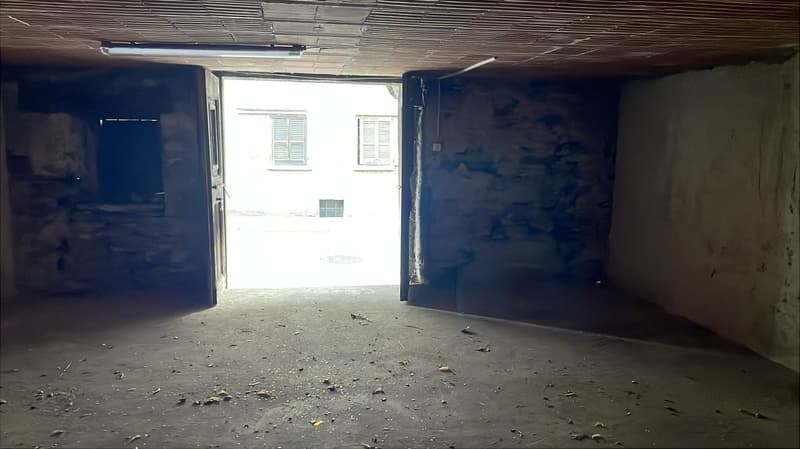 empty garage with 2 doors, small light on the ceiling, floor littered with debris