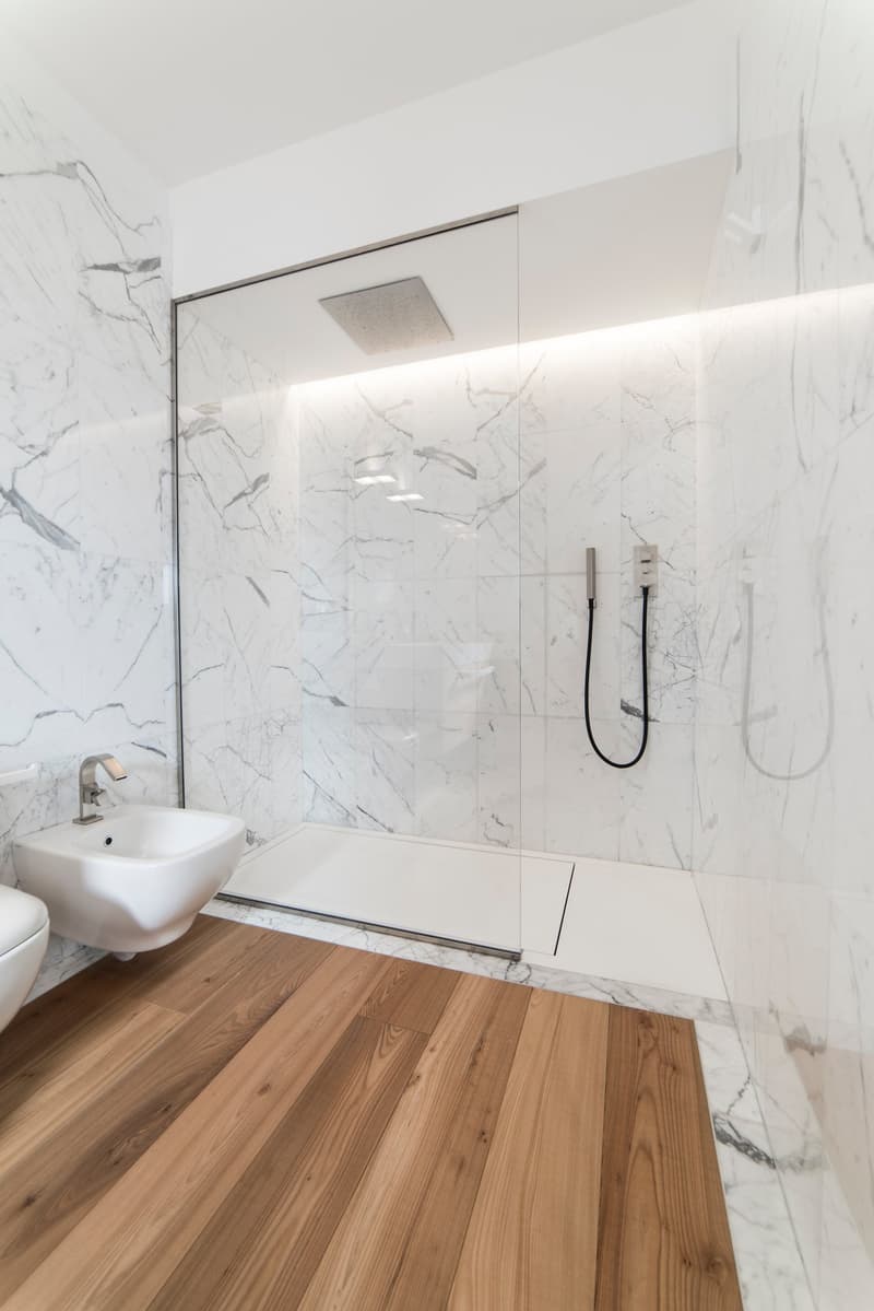 shower area with glass walls, white sink, white ceramic tiles, wooden floor, modern design