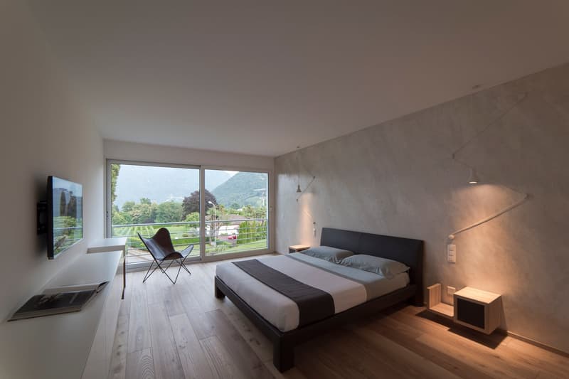 double bed, bedside tables, TV, balcony, modern decor, book on a shelf, large window, wall lamps
