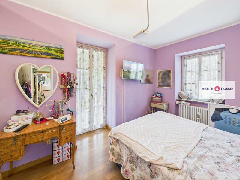 Bedroom with wooden desk, mirror, bed, and decorations on the wall
