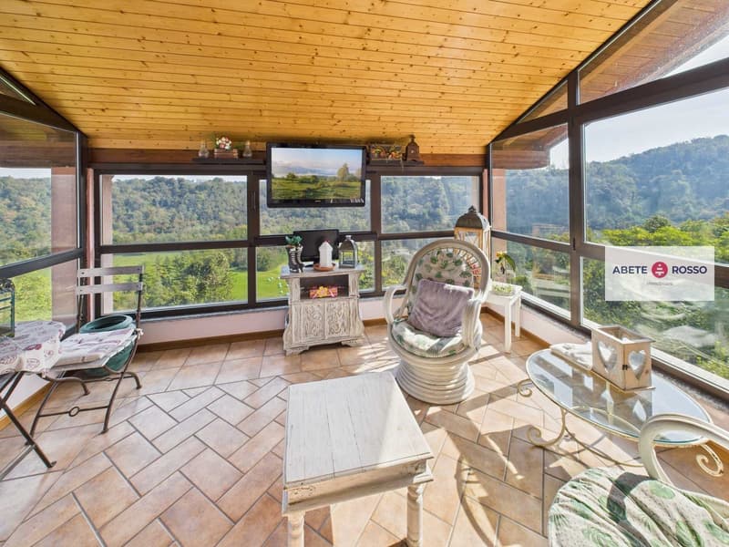 sun room with wooden ceiling, large windows, seating area, coffee table, side table, TV mounted on wall, framed mountain view