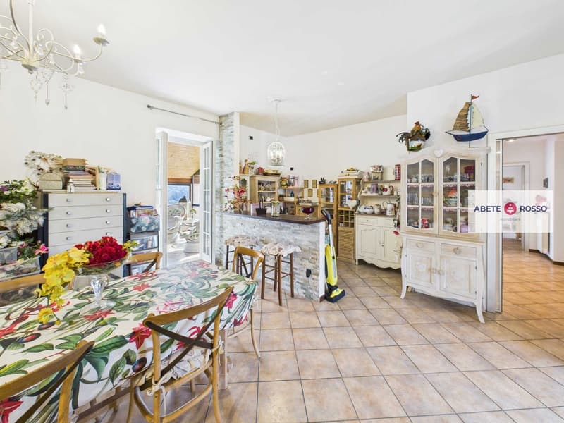 Dining room with table, chairs, buffet, wooden bar, kitchen elements, fireplace, chandelier, shelves, and decorations