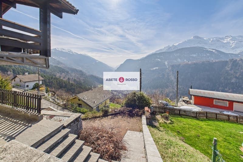 House with a view of the mountains, wooden fence, steps leading to the house, small garden, red house in the background