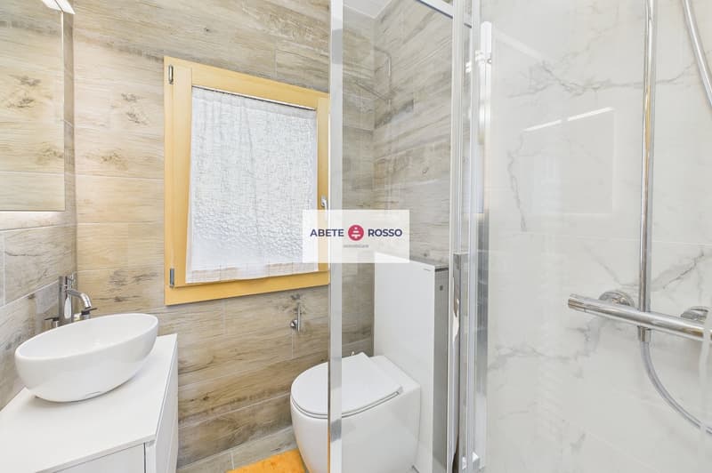 white marble tiles, wooden wall, white sink, white toilet, glass shower enclosure