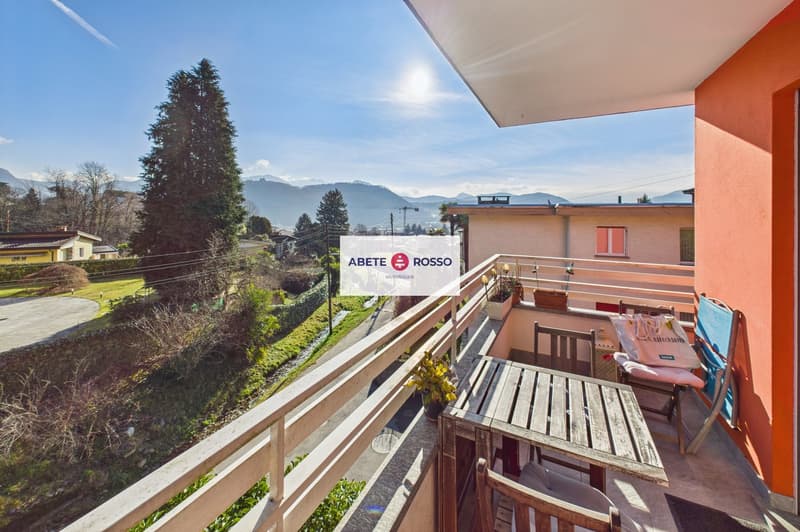 Balcony with wooden table and chairs, potted plants, and a view of the mountains