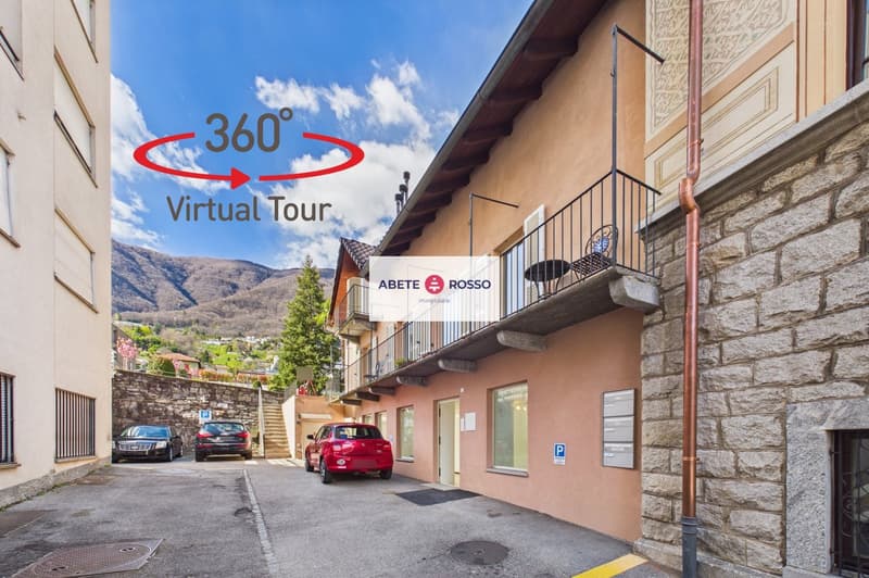 Building with stone walls, balcony with railings, parked cars, and a sign indicating a virtual tour.