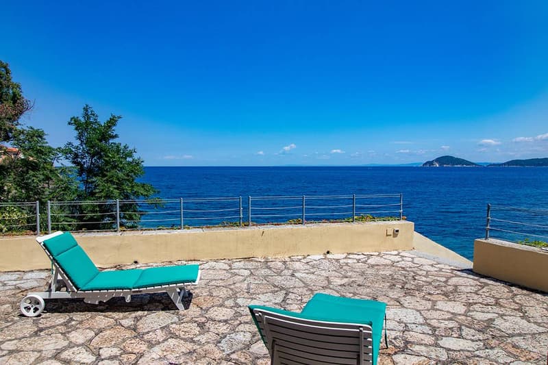 stone flooring, sun loungers, stone wall with railing, blue ocean