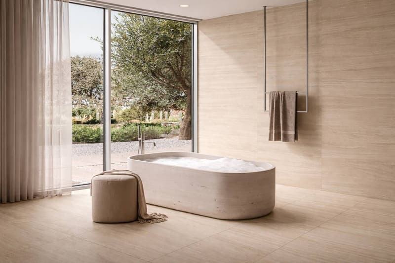 large bathtub, large window, beige tiles, white curtain, beige ottoman